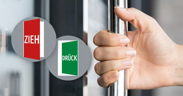 Hand öffnet eine Tür, links oben das Paar Navigadoor-Schilder - Modell Rondo links mit dem Text Zieh und Drück